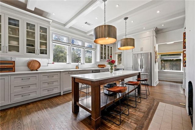 kitchen with beam ceiling, stainless steel fridge, dark wood finished floors, and light countertops