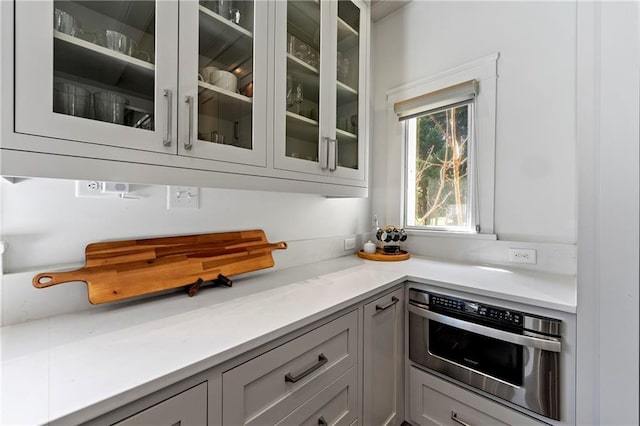 kitchen featuring glass insert cabinets, light countertops, and oven