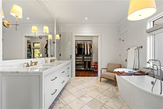 full bathroom with a freestanding bath, double vanity, ornamental molding, marble finish floor, and a sink