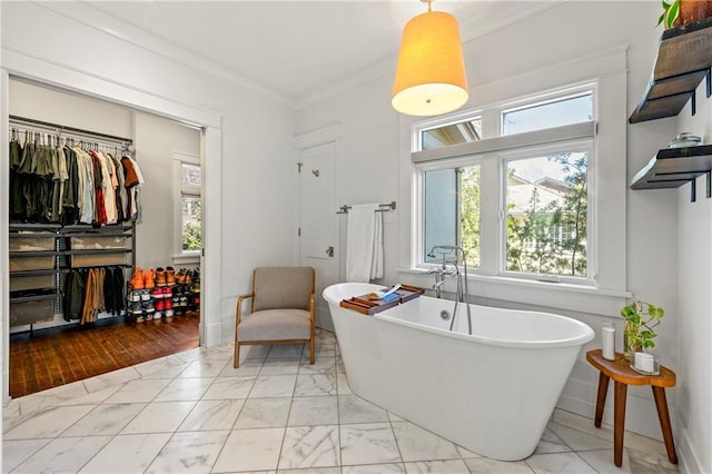 bathroom with crown molding, a freestanding tub, and marble finish floor