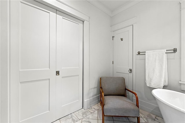 bathroom with marble finish floor, a freestanding tub, and ornamental molding