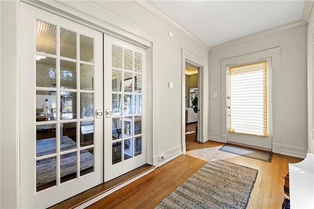 entryway featuring french doors, crown molding, baseboards, and wood finished floors