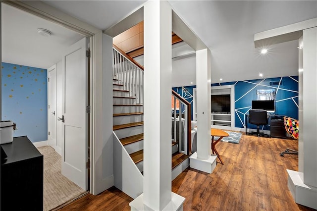 staircase with baseboards, wood finished floors, an accent wall, and wallpapered walls