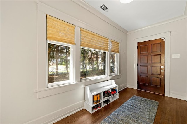 entryway with visible vents, baseboards, wood finished floors, and ornamental molding