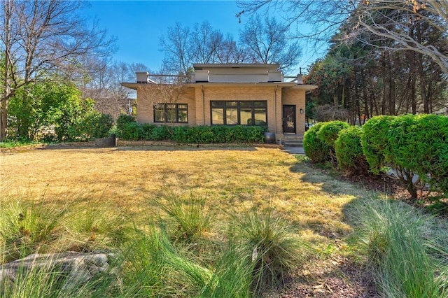 back of house with a lawn and brick siding