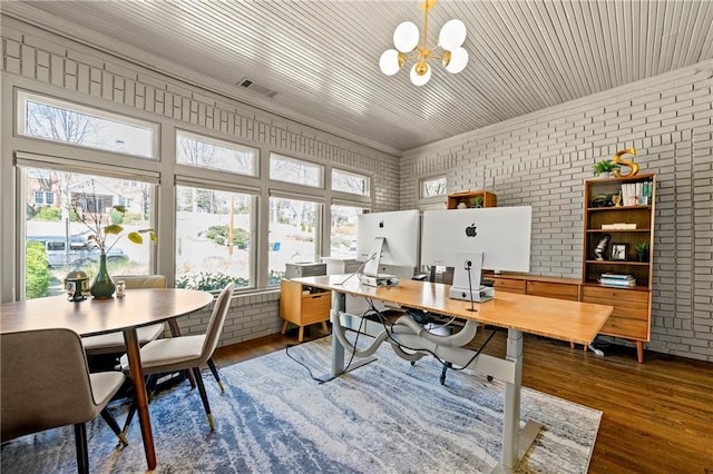 office with a chandelier, visible vents, dark wood finished floors, and brick wall