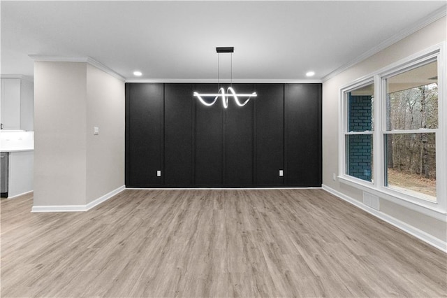 unfurnished dining area with ornamental molding, a chandelier, and light wood-type flooring