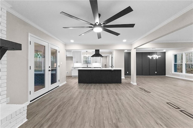 kitchen with white cabinetry, french doors, an island with sink, hanging light fixtures, and island range hood