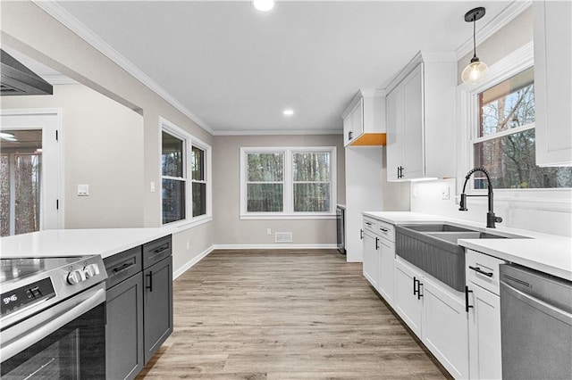 kitchen with white cabinetry, stainless steel appliances, sink, hanging light fixtures, and crown molding