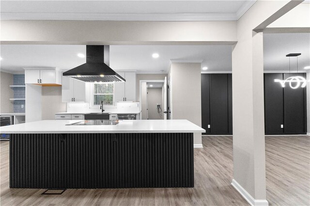 kitchen featuring light hardwood / wood-style flooring, white cabinets, ornamental molding, a kitchen island, and island range hood