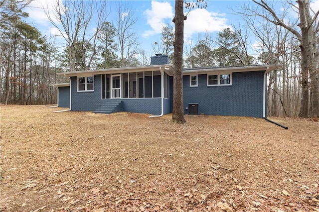 rear view of house with central air condition unit and a sunroom