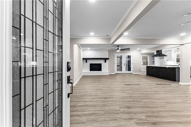 unfurnished living room with a fireplace, wood-type flooring, ceiling fan, and crown molding