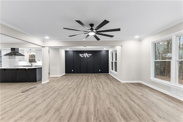 unfurnished living room featuring light hardwood / wood-style floors, a wealth of natural light, crown molding, and ceiling fan