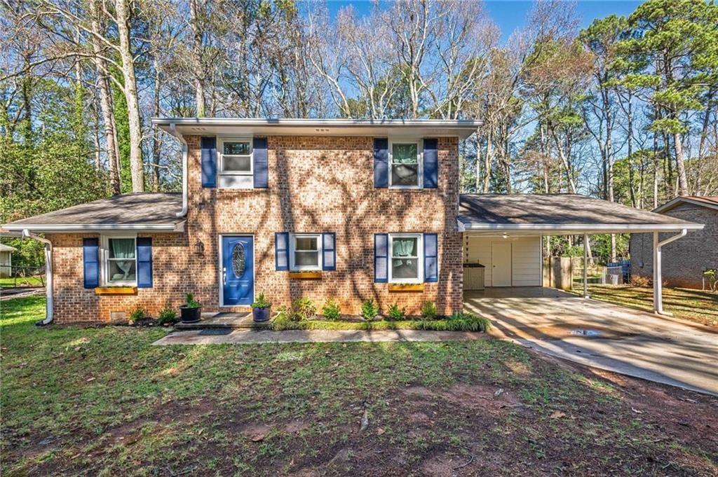view of front of property featuring brick siding, a front yard, a carport, and concrete driveway