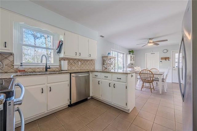 kitchen featuring light tile patterned floors, a peninsula, stainless steel appliances, and a sink