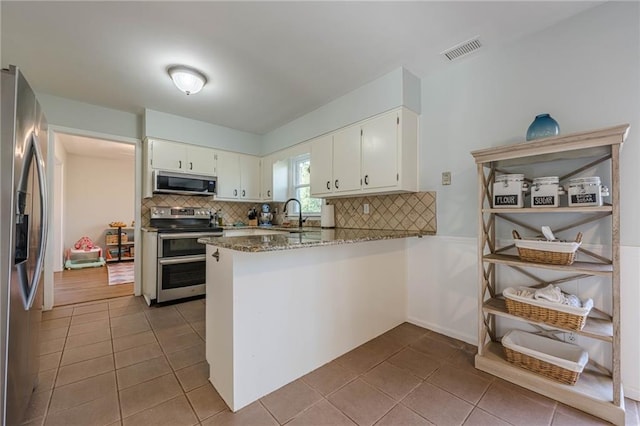 kitchen with tile patterned floors, visible vents, tasteful backsplash, appliances with stainless steel finishes, and a peninsula