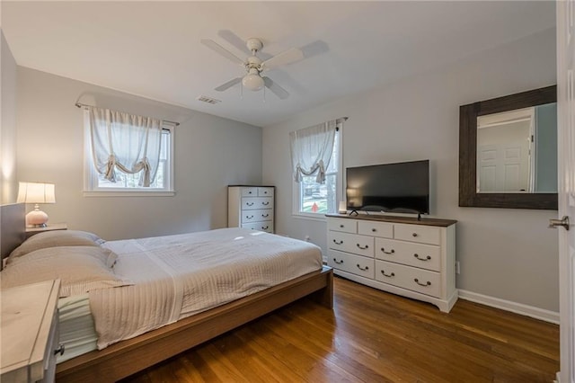 bedroom featuring baseboards, multiple windows, visible vents, and wood finished floors