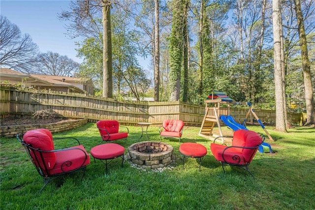 view of yard featuring a playground, fence, and a fire pit