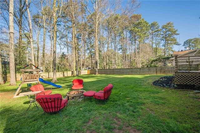 view of yard with a playground, a fenced backyard, and an outdoor fire pit