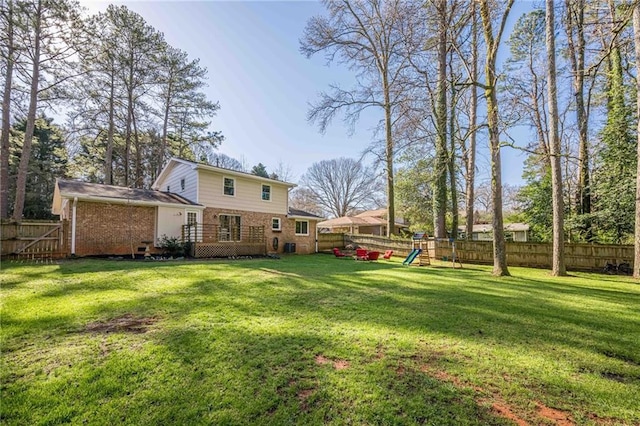 view of yard featuring a wooden deck, a playground, and a fenced backyard