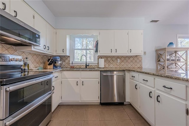 kitchen with a sink, stainless steel appliances, visible vents, and white cabinetry