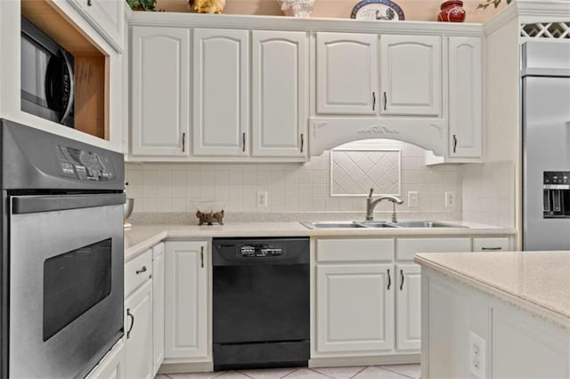 kitchen featuring light tile patterned floors, black appliances, sink, decorative backsplash, and white cabinets