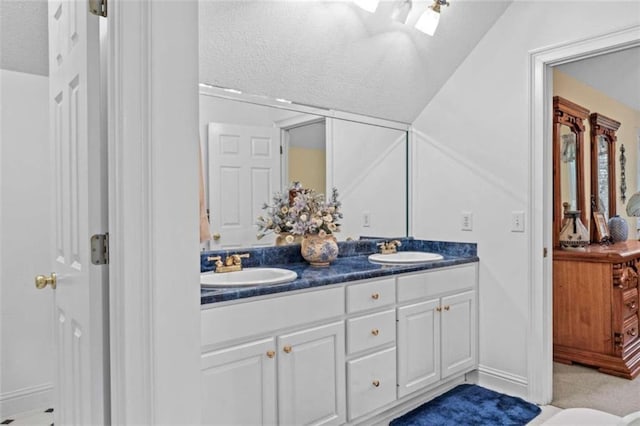 bathroom with vaulted ceiling, a textured ceiling, and vanity