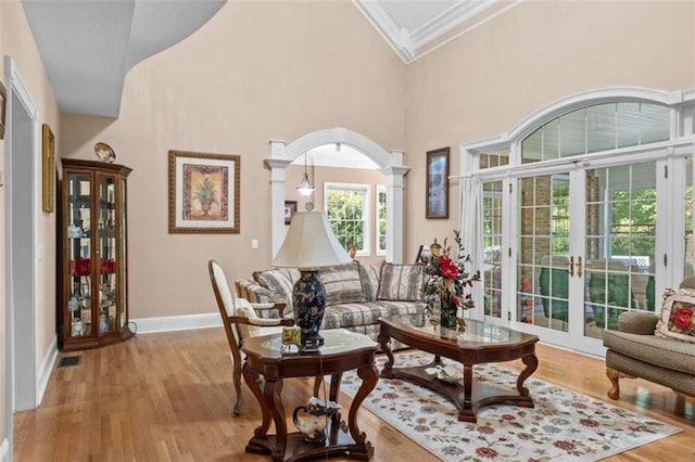 living room featuring crown molding, french doors, light hardwood / wood-style flooring, and a high ceiling