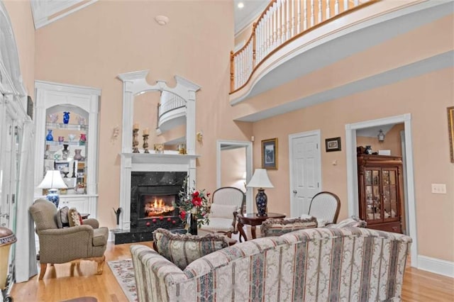 living room featuring light hardwood / wood-style flooring, a high ceiling, and a high end fireplace