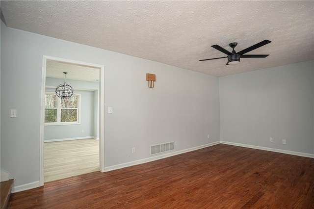 spare room featuring baseboards, wood finished floors, visible vents, and a ceiling fan