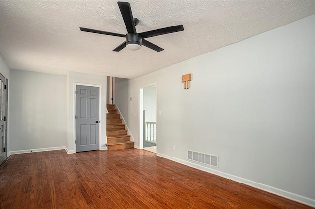 spare room with visible vents, ceiling fan, wood finished floors, baseboards, and stairs