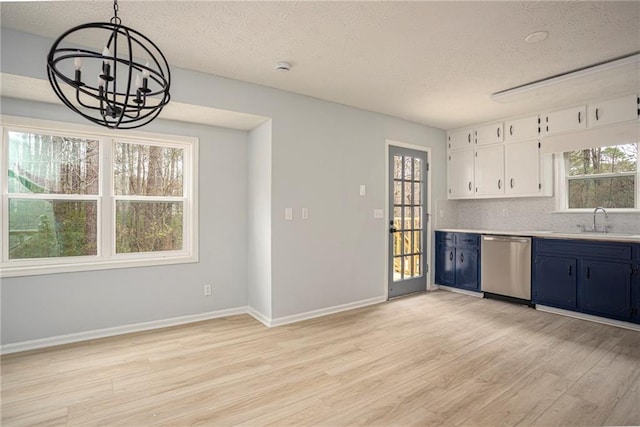 kitchen with blue cabinetry, light countertops, stainless steel dishwasher, a sink, and light wood-type flooring