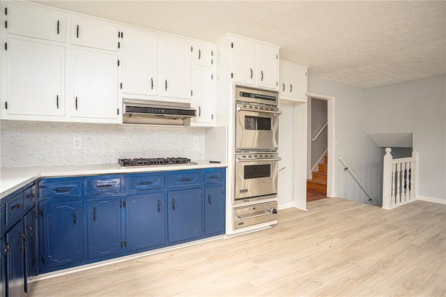 kitchen featuring white cabinets, light wood-style flooring, blue cabinets, stainless steel appliances, and under cabinet range hood