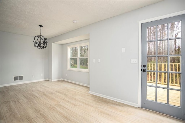 interior space featuring visible vents, light wood-style flooring, a textured ceiling, a chandelier, and baseboards