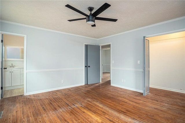 unfurnished bedroom with ornamental molding, hardwood / wood-style floors, a textured ceiling, and baseboards