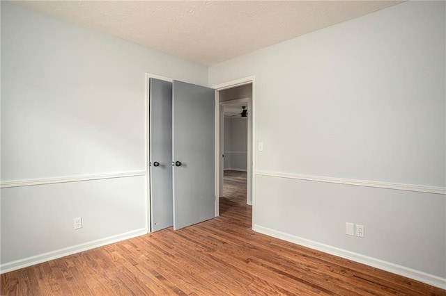 spare room featuring a textured ceiling, baseboards, and wood finished floors