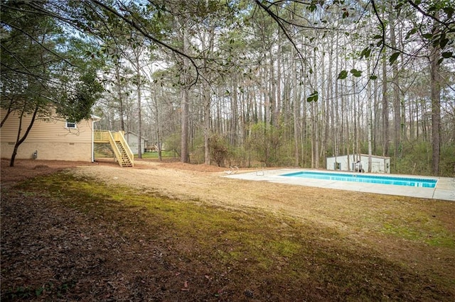 view of yard with an outbuilding, an outdoor pool, and stairway