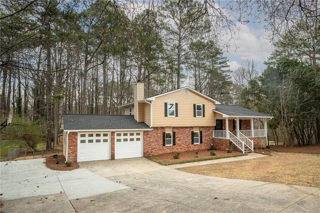 tri-level home with concrete driveway, a chimney, an attached garage, a porch, and brick siding