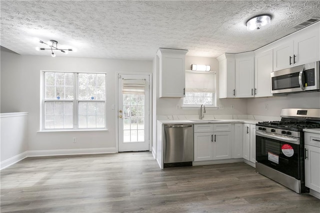 2682 Field Spring Dr, Lithonia, GA 30058 - kitchen featuring stainless steel appliances, a sink, wood finished floors, light countertops, and white cabinetry