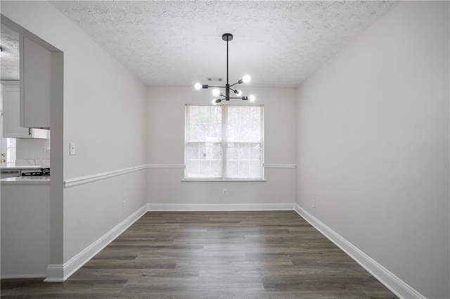 2682 Field Spring Dr, Lithonia, GA 30058 - unfurnished dining area featuring a chandelier, a textured ceiling, dark wood-type flooring, and baseboards
