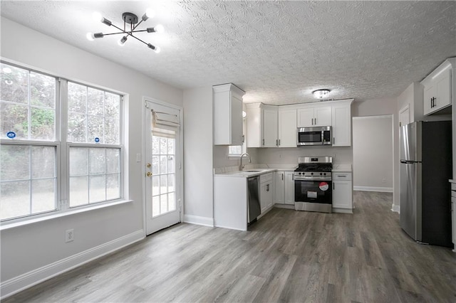 2682 Field Spring Dr, Lithonia, GA 30058 - kitchen featuring stainless steel appliances, wood finished floors, a chandelier, a sink, and a textured ceiling