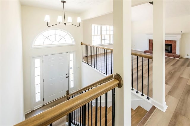 entrance foyer with baseboards, a towering ceiling, wood finished floors, an inviting chandelier, and a fireplace