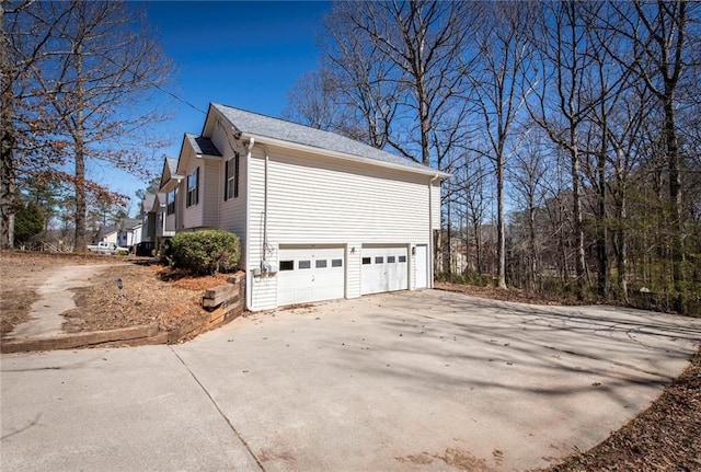 view of side of home featuring a garage and concrete driveway