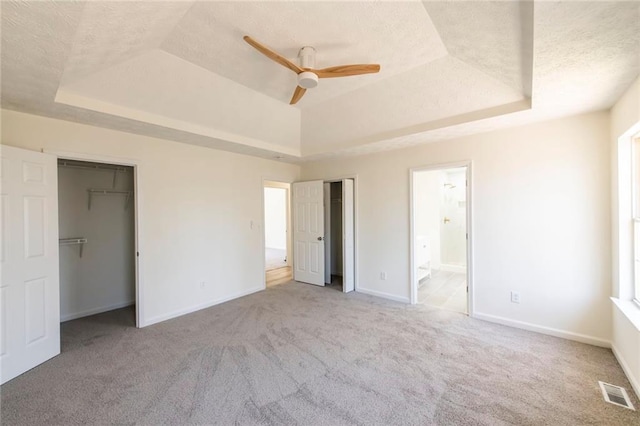 unfurnished bedroom featuring a tray ceiling, visible vents, carpet flooring, a textured ceiling, and baseboards