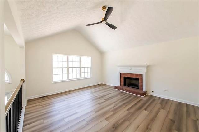 unfurnished living room featuring ceiling fan, wood finished floors, vaulted ceiling, a textured ceiling, and a fireplace