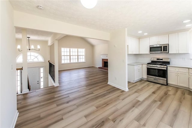 kitchen featuring white cabinets, appliances with stainless steel finishes, open floor plan, and light countertops