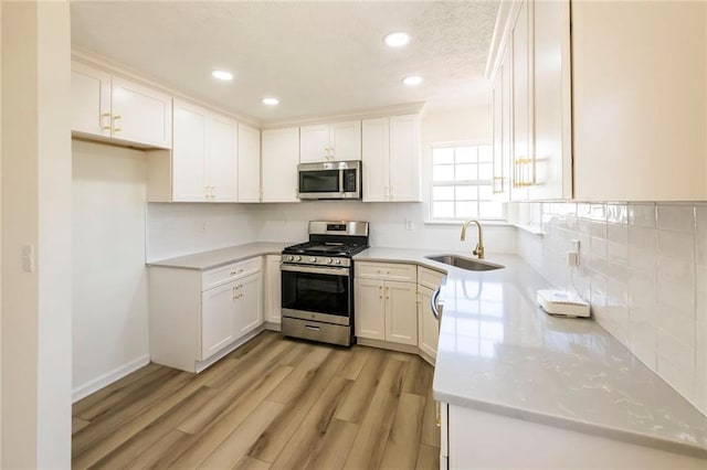 kitchen with stainless steel appliances, light wood-type flooring, a sink, and decorative backsplash