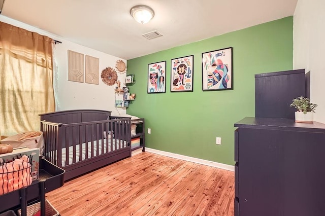 bedroom with hardwood / wood-style floors and a nursery area