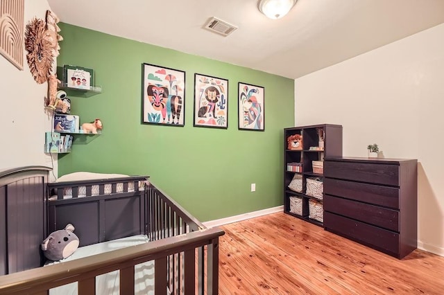 bedroom featuring a crib and light wood-type flooring