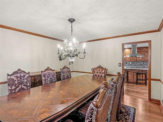 dining area with light wood-type flooring, an inviting chandelier, a textured ceiling, and crown molding